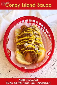 a hot dog with mustard and onions in a red basket on a white counter top