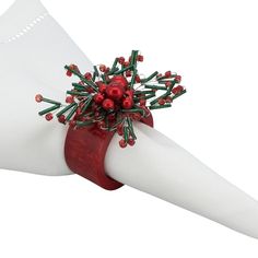 a napkin holder with red and green decorations on it's side, sitting on top of a white napkin