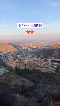 the city is surrounded by hills and trees, with two hearts on each side that read amer, jajpur