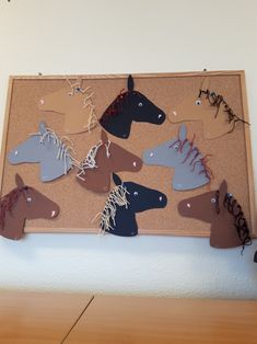 a cork board with several different colored horses hanging from it's sides on a wall