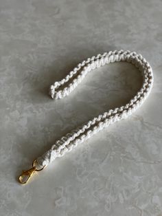 a white rope with gold clasps is on the floor next to a pair of scissors