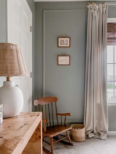 a room with a chair, lamp and pictures on the wall