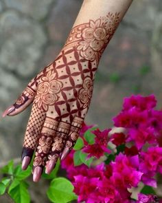 a woman's hand with henna on it and pink flowers in the background