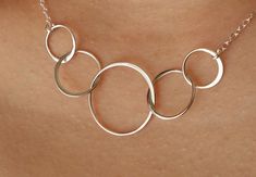 a woman wearing a silver necklace with three circles on it