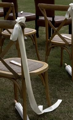 several chairs with bows tied to them in the grass