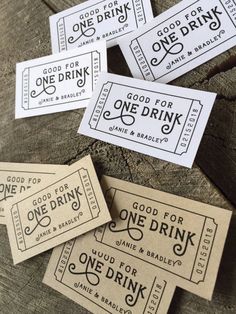 four tickets with the words good for one drink are sitting on top of a piece of wood