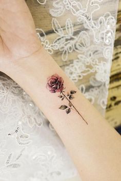 a woman's arm with a rose tattoo on the left side of her wrist