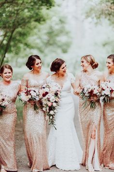 a group of women standing next to each other wearing dresses and holding bouquets in their hands