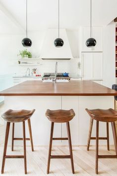 three stools sit at the center of a kitchen island