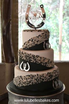 a three tiered cake is decorated with black and white frosting, horseshoes and pearls