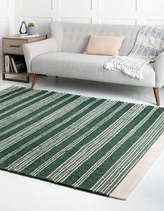 a living room with a white couch and green striped rug on the floor in front of it