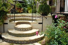 a set of stone steps leading up to an outdoor patio area with flowers and greenery