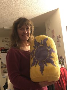 a woman holding a yellow and purple knitted object