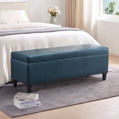 a blue bench sitting on top of a carpeted floor next to a white bed