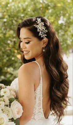 a woman in a wedding dress holding a bouquet and wearing a bridal hair comb