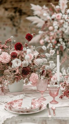 the table is set with pink and white flowers in vases, candlesticks, and plates