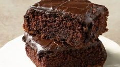 two pieces of chocolate cake sitting on top of a white plate next to each other