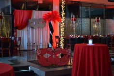 a red table cloth with some decorations on it and lights in the background at a party