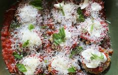 a green bowl filled with meat covered in sauce and parmesan cheese on top