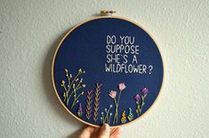 someone is holding up a embroidery art piece with flowers on it that says do you suppose she's a wildflower?