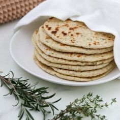 a white plate topped with pita bread next to a sprig of rosemary