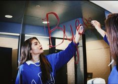 two girls writing the word blvd on a mirror