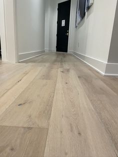 an empty room with white walls and wood floors is seen in this image from the front door