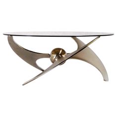 a glass and metal coffee table with an abstract design