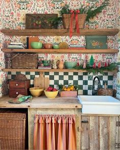 an old fashioned kitchen is decorated with colorful wallpaper and wooden shelves filled with dishes