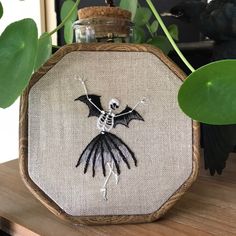 a cross stitch halloween decoration with a skeleton and bat on it