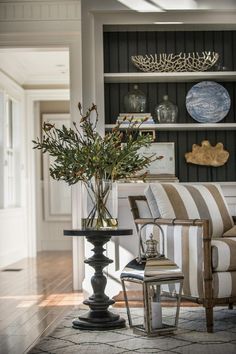 a living room filled with furniture and a vase on top of a coffee table in front of a bookshelf