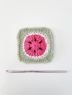 a crocheted square with a pink and green watermelon on it next to a knitting needle