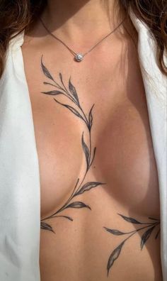 a woman's chest with tattoos on it and leaves drawn on the chest piece