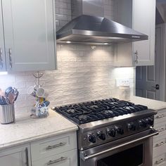 a stove top oven sitting inside of a kitchen next to white cupboards and drawers