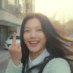 a woman with long black hair is giving the peace sign and smiling at the camera