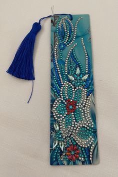 a blue bookmark with beads and tassels on the front, sitting on a white surface