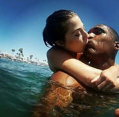 a man and woman are kissing in the water on a sunny day at the beach