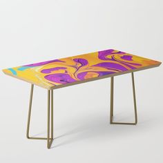 a table with an abstract design on the top and gold metal legs, against a white background