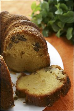 a loaf of cake sitting on top of a white plate next to a green plant