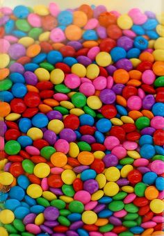 there are many different colored candies in the bowl together, and they look like candy