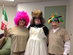 three people dressed up in costumes and wigs posing for the camera with one woman holding a flag