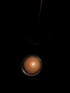 a lit candle sitting on top of a table in the middle of the dark room