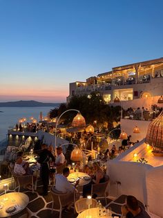 people are sitting at tables on the roof of a restaurant overlooking the water and buildings