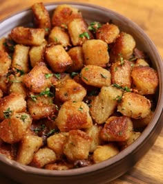 a brown bowl filled with fried food on top of a wooden table