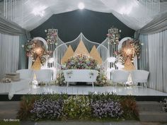 the stage is decorated with white chairs and flowers