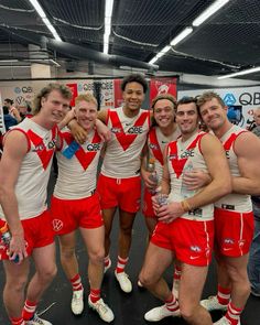 a group of men standing next to each other wearing red and white uniforms on top of a black floor