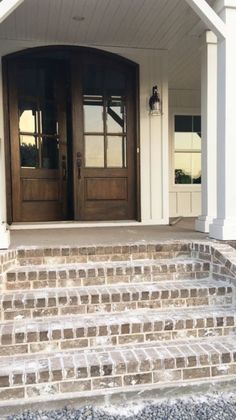 the front entrance to a house with two double doors and steps leading up to it