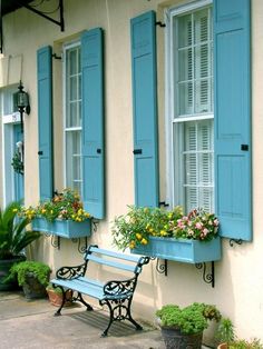 blue shuttered windows and bench in front of a building with potted plants on it