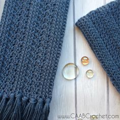 a knitted scarf next to buttons on a wooden surface