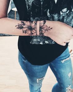 a woman with a flower tattoo on her arm and wrist is standing in front of the camera